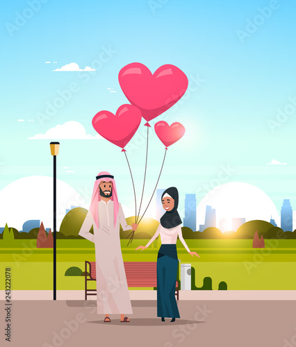 arab man giving woman pink heart shape air balloons happy valentines day concept arabic couple in love over city urban park cityscape background flat vertical