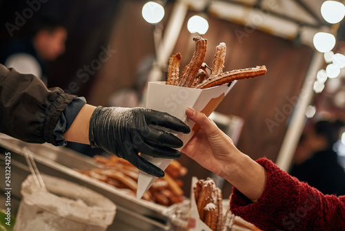Close-up of young blonde woman buying churros photo