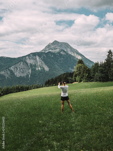 Rear view of woman taking picture of mountain peak with smartphone