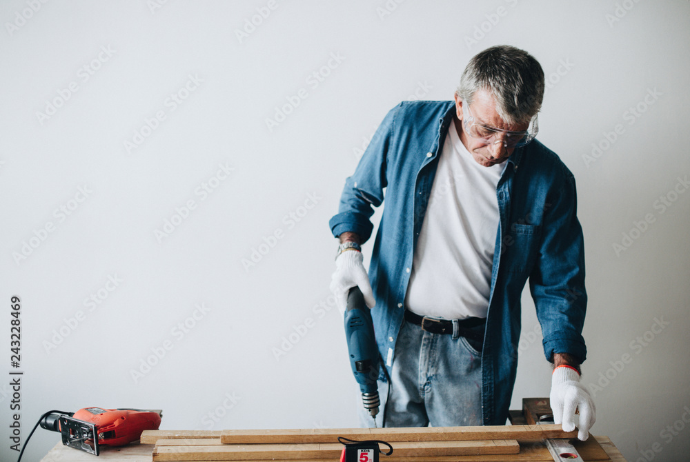 Man using a hand driller with a plank Man using a hand driller with a plank