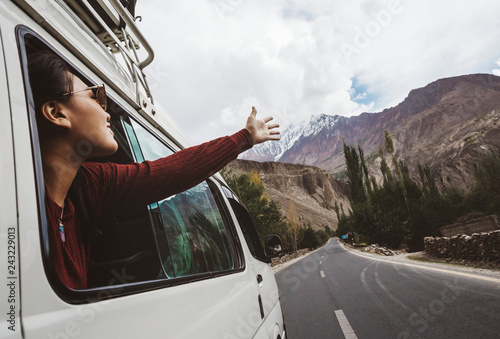 Young woman enjoying traveling by car across mountain landscape