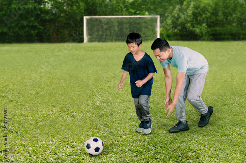 Young man playing football with his son © Creativa Images