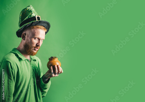 St patricks day. Patricks Day Pot of Gold and shamrocks. Red hair man in Saint Patrick's Day leprechaun party on green background. Copy space. photo