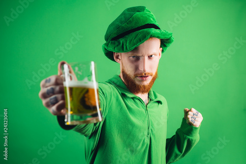 Man on green background celebrate St Patricks Day. Portrait of excited man holding glass of beer on St Patrick's day isolated on green. photo
