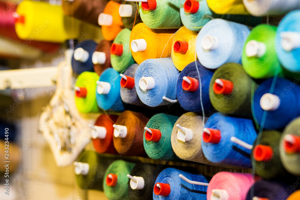 Colorful cones and spools of thread at an atelier.Tailoring, garment industry, designer workshop concept. embroidery thread spool.row of multicolored yarn rolls, sewing material.Workplace of tailor