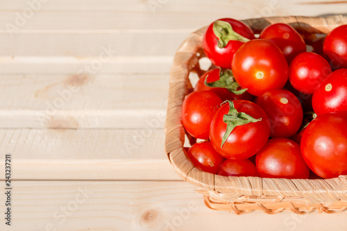 Many tomatoes called cherry tomato in the basket on wooden table, fresh organic vegetables freshly harvested from local farmers.ripe tomatoes in wicker wooden bowl.Copy space