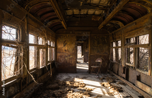 Interior of rusted vintage rail car with natural light coming through the windows.  