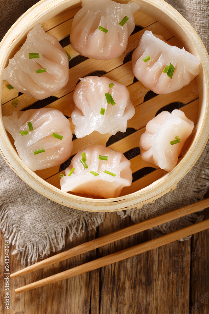Homemade dumplings dim sum with stuffed shrimp close-up in a bamboo steamer box. Vertical top view