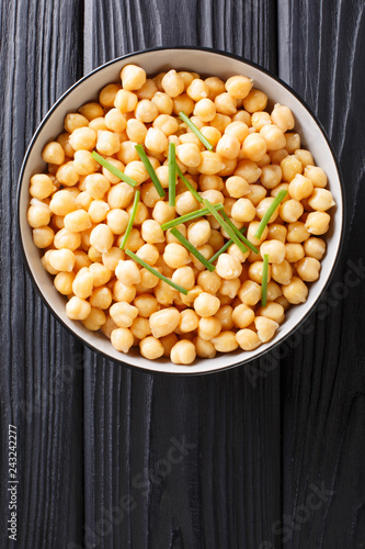 Fresh boiled organic chickpeas with green onions close-up in a bowl. Vertical top view