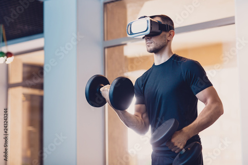 Man wearing virtual reality glasses with dumbbells