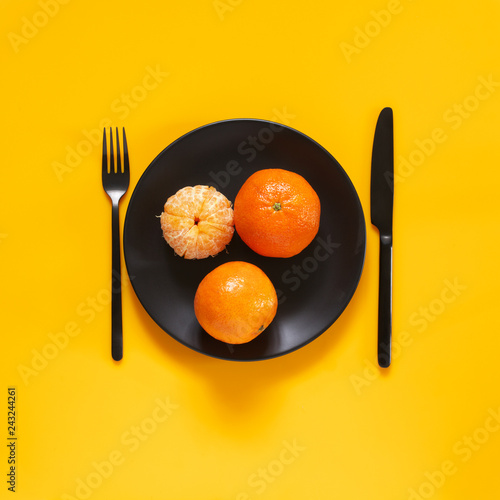 Tangerines in black plate on yellow