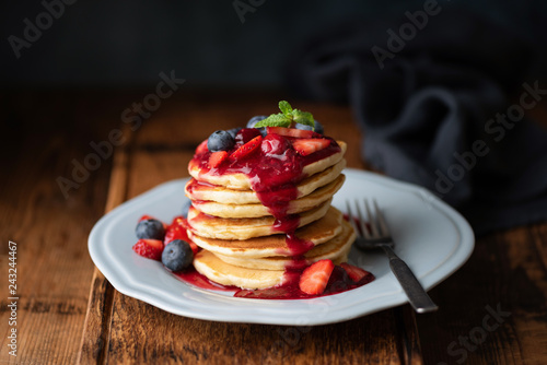 Tasty Pancakes With Berry Sauce On Wooden Table. Closeup view. Low Key Food Photography