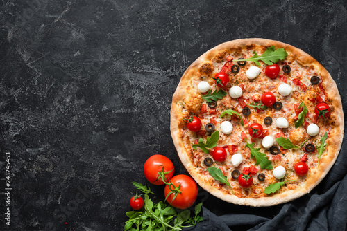 Tasty pizza with tomatoes and mozzarella on black background. Top view, copy space for text. Hot Italian pizza