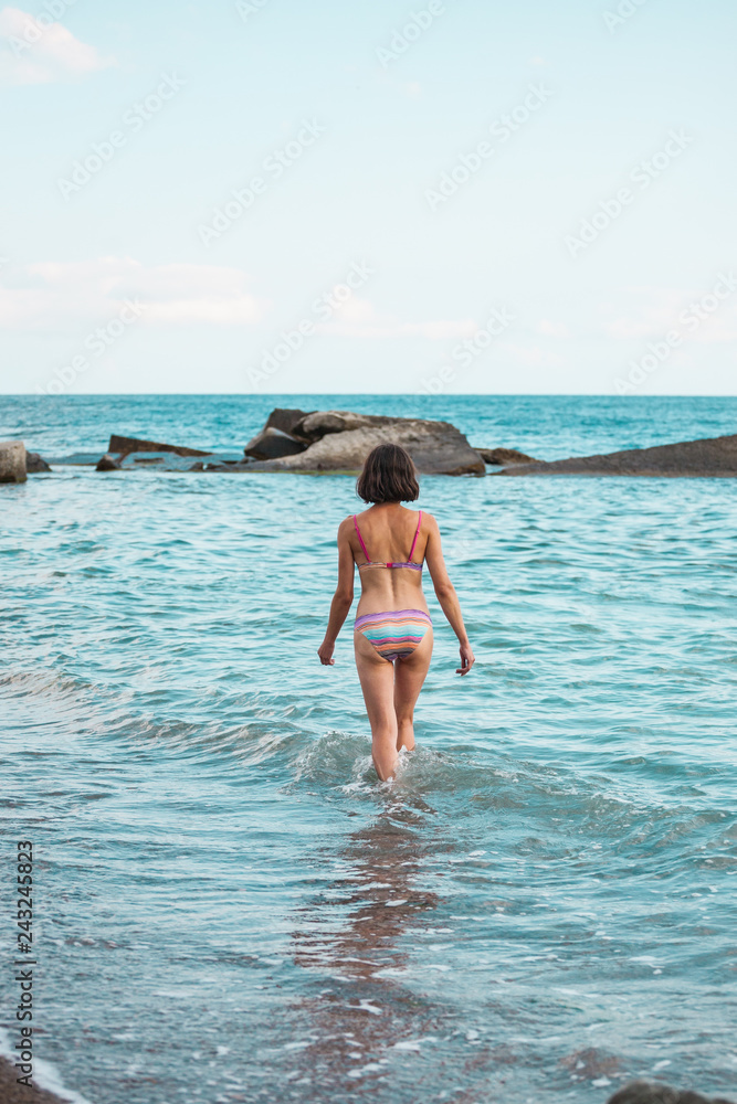 The girl goes into the sea water.