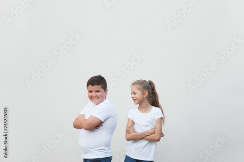 beautiful happy smiling young fat boy and thin little girl in white shirt on bright background with copy space