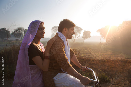 Side view of couple in traditional dress riding on bicycle photo