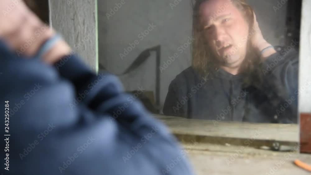 Depressed and angry man is sitting in front of his reflection in an old abandoned house Depressed and angry man is sitting in front of his reflection in an old abandoned house