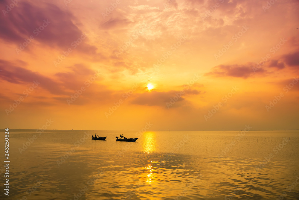 Beautiful sunrise on the beach and silhouette of fishing boat.Thailand.