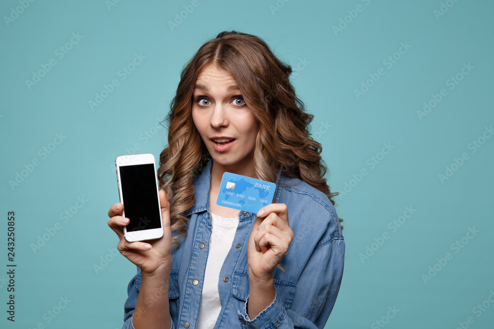 Image of excited young lady isolated over blue background using mobile phone holding credit card. Image of excited young lady isolated over blue background using mobile phone holding credit card.