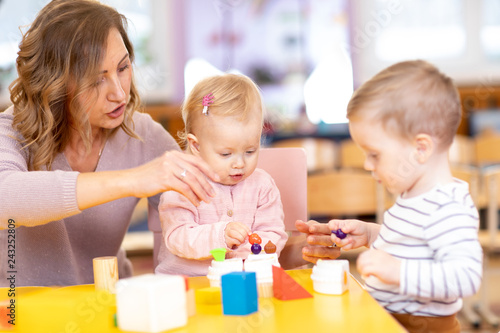 Nursery teacher with children boy and girl learn color and size while playing together. Early education concept.