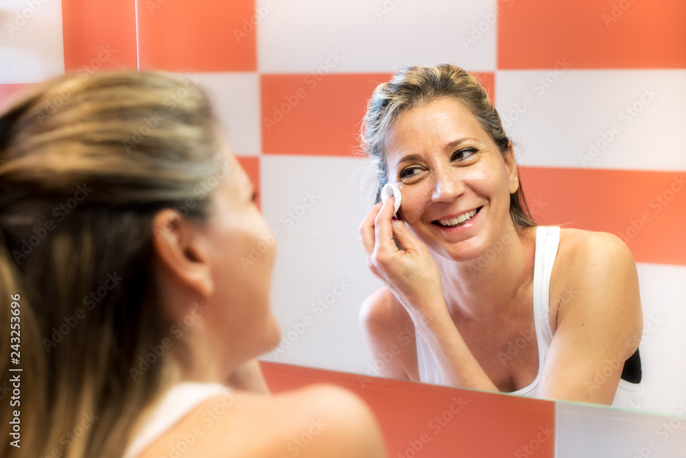 Smiling woman removing makeup Smiling woman removing makeup