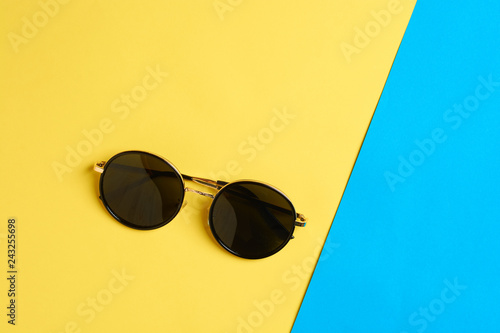 Flat lay. Top view. Fashion sunglasses on yellow and blue background with copy space. Summer concept