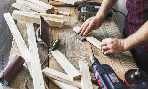 Carpenter working carpentry workshop Man sanding manually plank photo