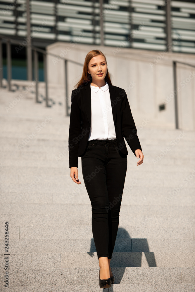 Young business woman walk on stairs leaving office building