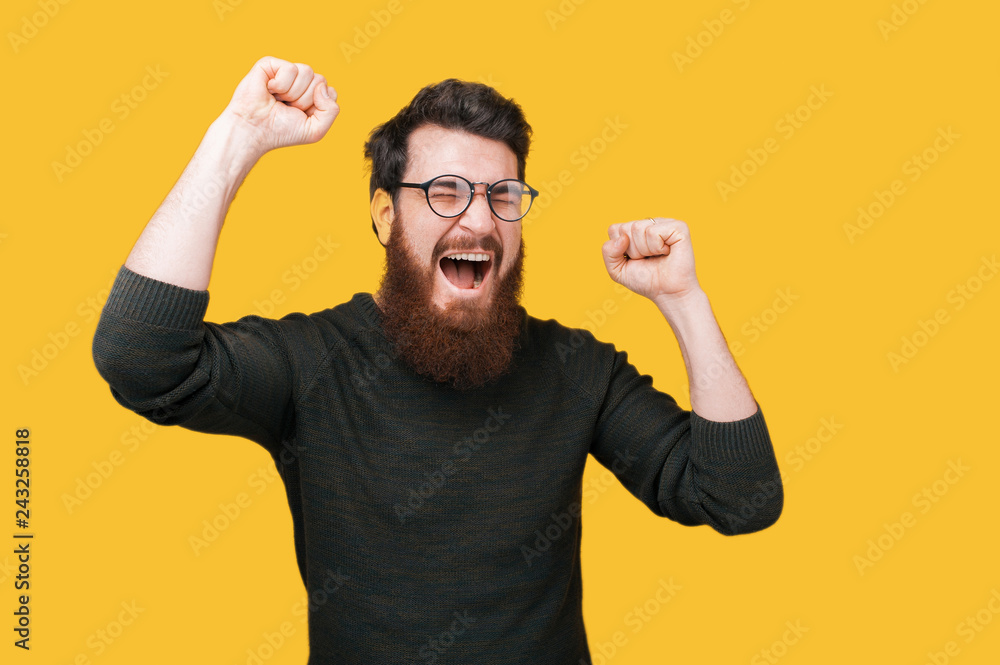 Man with beard celebrating success or victory over yellow background Man with beard celebrating success or victory over yellow background