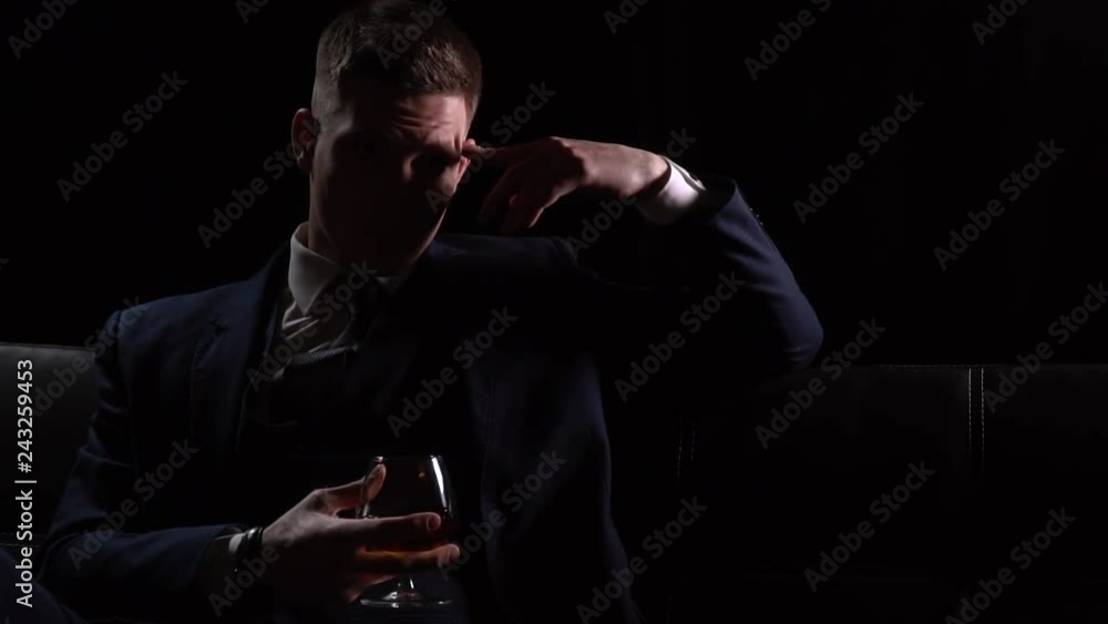 Businessman in a three piece suit, sitting on a couch with a glass of whiskey and thinking Businessman in a three piece suit, sitting on a couch with a glass of whiskey and thinking