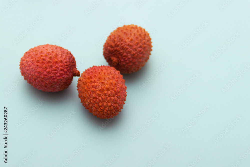three lychee fruits lie on a turquoise blue background three lychee fruits lie on a turquoise blue background