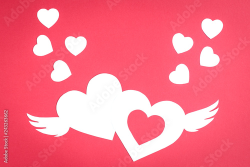 Two white paper hearts with wings on red back ground with copy space. Valentine's day concept. 