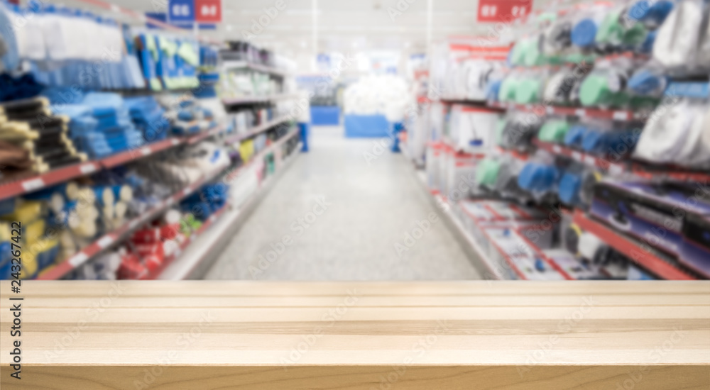 Wooden table top in front of blurred hardware and grocery store. Background for product display montage. Copy space design.