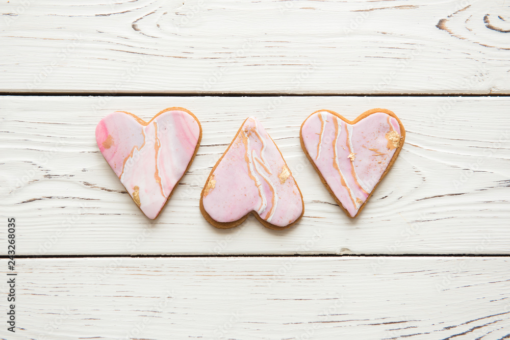 Obraz premium Three cookies in the shape of marble white hearts on wooden background