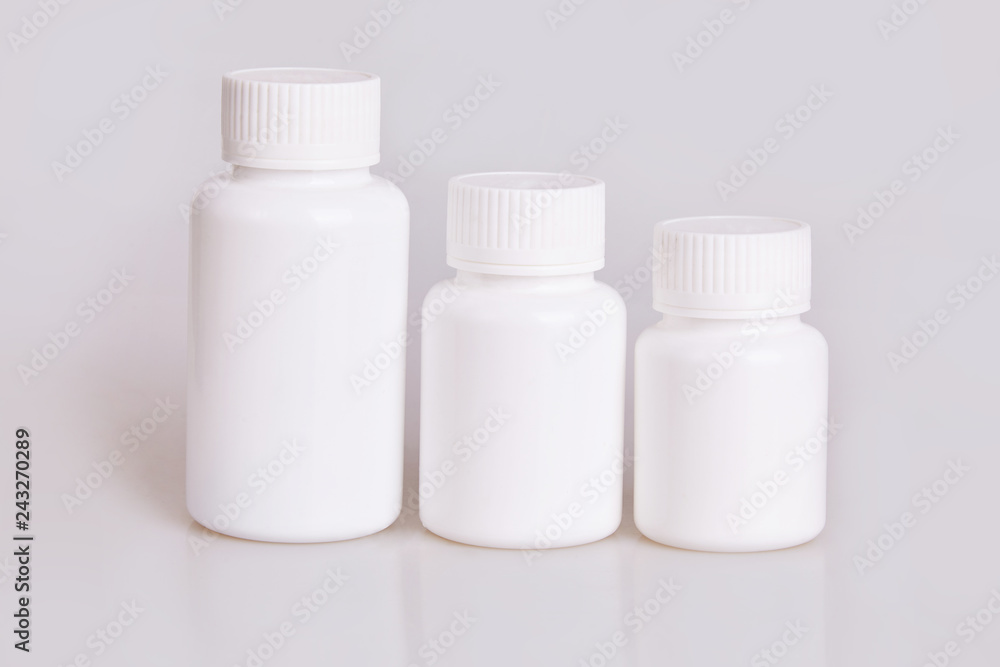 White blank medical plastic bottles of different sizes on a white background. Studio lights White blank medical plastic bottles of different sizes on a white background. Studio lights