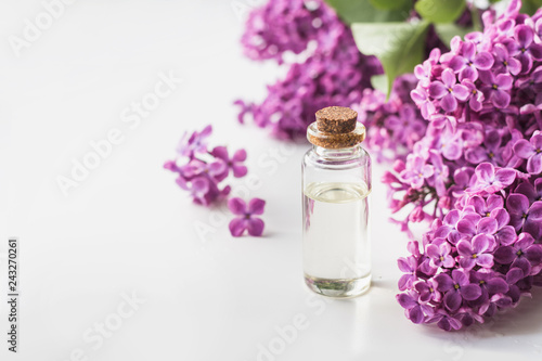 Glass jar with rose water and lilac flowers, copy space for text. Concept for spa and aromatherapy. Close up.