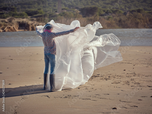 Girl entangled in waving textile on river coast
