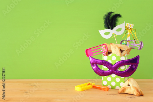 Purim celebration concept (jewish carnival holiday) over wooden table and green background.