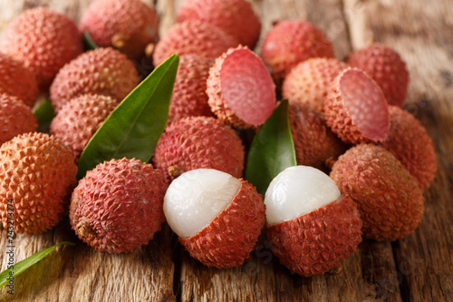 Fresh lychee and peeled showing the red skin and white flesh with green leaf. horizontal