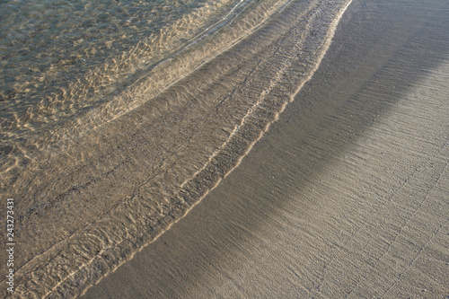 The texture of sand in the flickering light of the coastal waves at sunset. Well suited for creating textures, printing panels and abstract interior posters. © MARINA KUMA