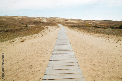 Stairs to the beach. A wooden staircase leads to a wide sandy beach on the picturesque shore on a beautiful and windy summer day.