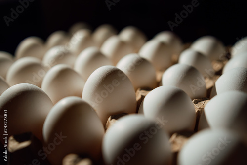 Top view of opened box with eggs on black background. Fresh chicken eggs closeup