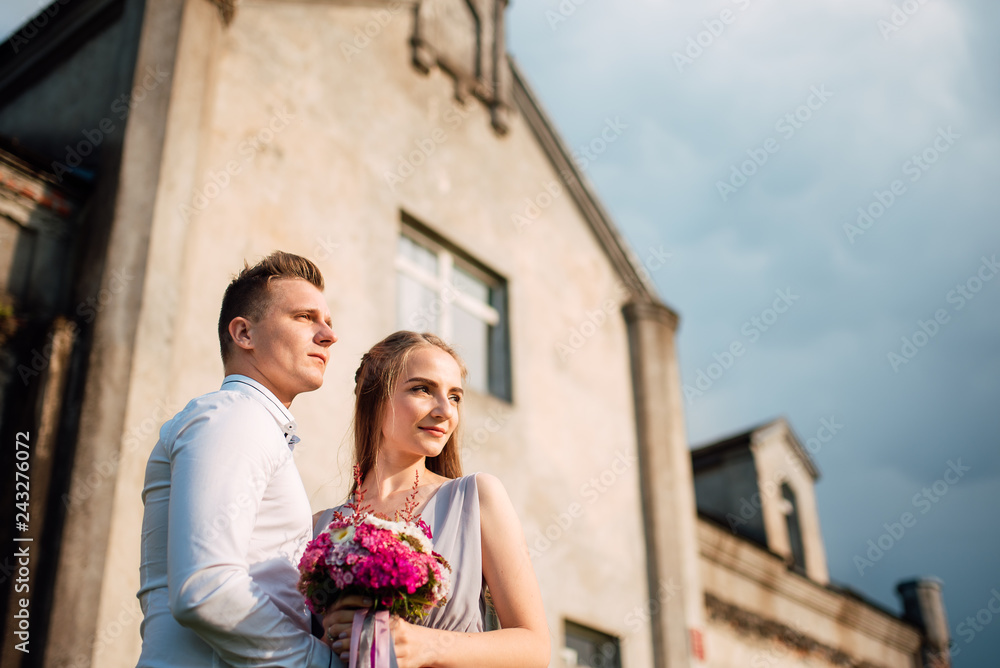 Young cute bride with bouquet of flowers hugging the groom on nature. Beautiful wedding couple outdoor portrait. Portrait of a loving couple. Wedding photo session. Second half. Newlywed