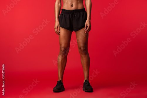 Cropped image of african american woman in black sportswear standing, isolated over red background