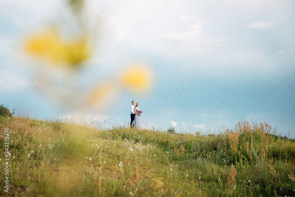 Young cute bride with bouquet of flowers hugging the groom on nature. Beautiful wedding couple outdoor portrait. Portrait of a loving couple. Wedding photo session. Second half. Newlywed