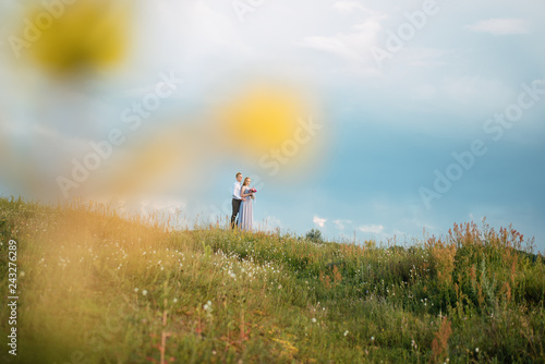 Fototapeta Naklejka Na Ścianę i Meble -  Young cute bride with bouquet of flowers hugging the groom on nature. Beautiful wedding couple outdoor portrait. Portrait of a loving couple. Wedding photo session. Second half. Newlywed