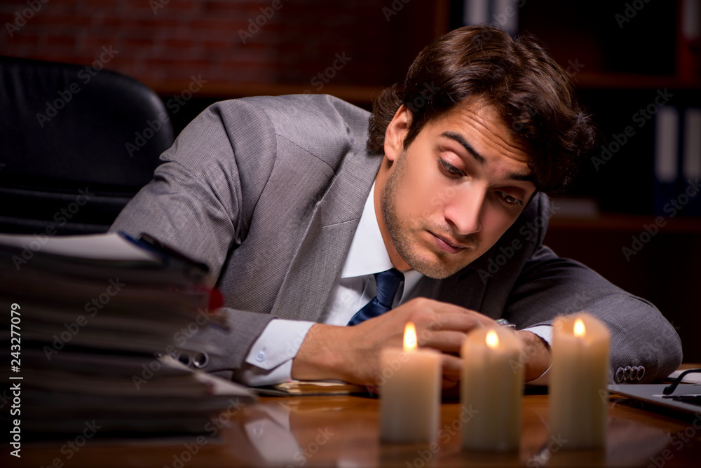 Obraz premium Businessman working late in office with candle light