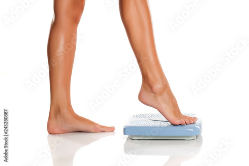 Young woman standing on a scale on white background