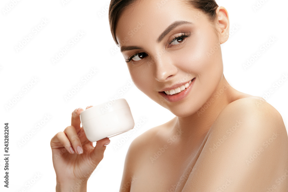 Cute girl preparing to start her day. She is applying moisturizer cream on face at studio. Cute girl preparing to start her day. She is applying moisturizer cream on face at studio.