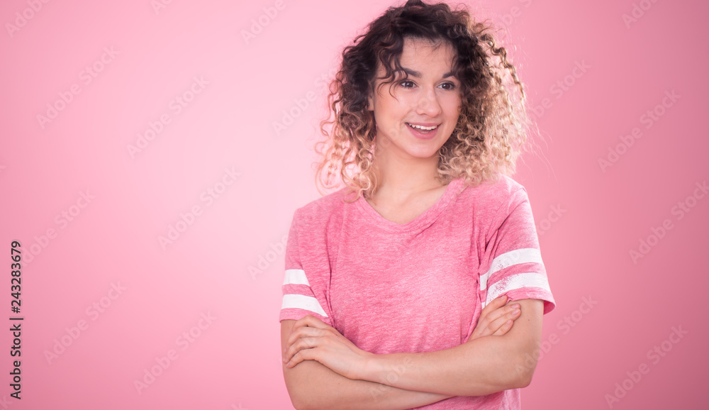 Fototapeta premium Portrait of a beautiful cheerful girl with curly hair on a pink background